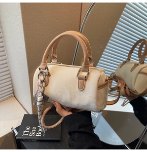 Close-up of cream Boston bag with brown handles and natural light shadow details