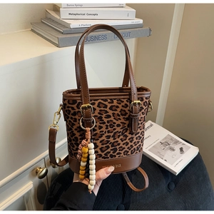 Détail du sac seau imprimé léopard avec base en cuir et breloque en perles colorées