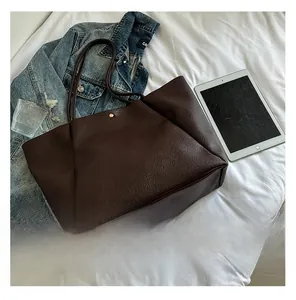 Close-up of dark brown lychee texture leather tote bag with a golden snap button