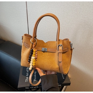 Détail du sac à main en daim marron avec boucle en cuir et breloques en perles de bois