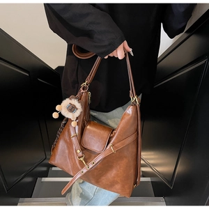 Detail of vintage brown PU leather tote with lion charm and adjustable shoulder strap