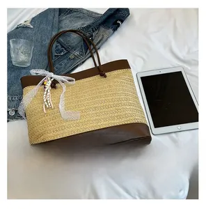 Detail der Strohtasche mit braunem Lederbesatz und süßer weißer Spitzenschleife Anhänger