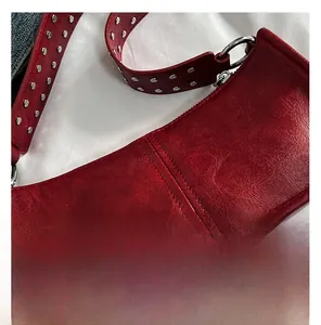 Detail of red vintage leather shoulder bag with silver metal rivet studs on strap