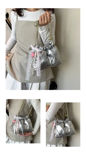 Detail view of silver quilted bucket bag with gold chain and decorative lace bow