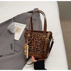 Détail du sac seau à imprimé léopard avec bordure en cuir marron et bijou de sac