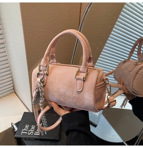 Pink Boston bag detail showing matte texture, golden hardware and woven rope charm