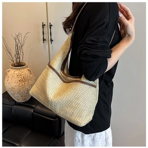 Detail of hand-woven straw tote bag with brown faux leather trim and sturdy shoulder strap