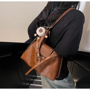 Detail view of retro brown leather tote bag with charm on a shoulder strap