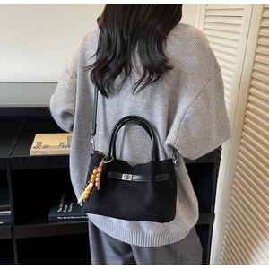Détail du sac seau noir en similicuir suédé avec charme en perles et fermoir en métal tournant