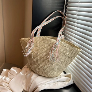 Large summer straw woven tote bag with colorful handles and tassels in natural sunlight