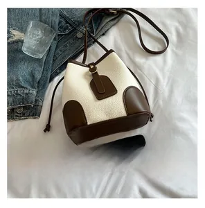 Close-up of contrast bucket bag with cream pebbled leather and brown trim details