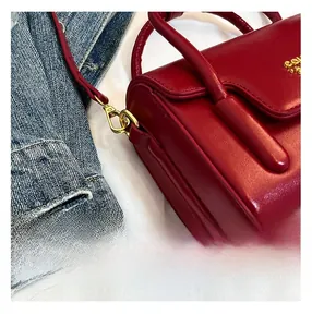 Détail de la texture cuir rouge et des finitions dorées d'un sac bandoulière vintage