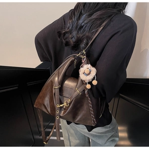 Detail of dark brown leather tote with golden hardware and fashion logo text