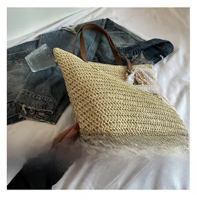 Detail of straw woven bucket bag with lace trim and brown leather handle on bed