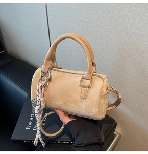 Detail of beige Boston bag with frosted texture and dual-color braided rope charm