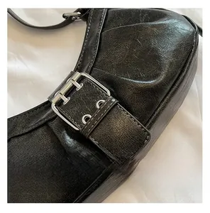 Detail shot of black crackle leather crescent bag with large silver square buckle