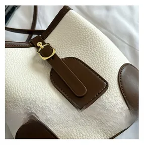 Detailed close-up of pebble grain leather texture and fine stitching on bucket bag