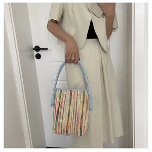 Detail of colorful striped woven bucket bag with light blue leather handle and metal rings