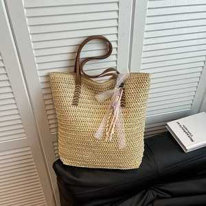 Large straw woven bucket bag with leather strap and decorative white lace pendant