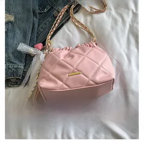 Close-up of pink quilted bucket bag with golden chain strap and decorative charms