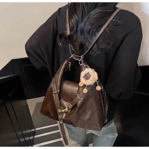 Close-up of a dark brown PU leather tote bag with a plush lion charm and adjustable strap
