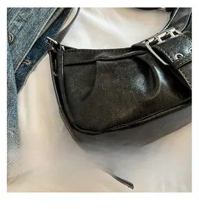 Close-up of black glossy wrinkled leather bag with silver metal buckle details