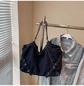 Detail of blue denim tote bag with contrast stitching and metal chain handle style