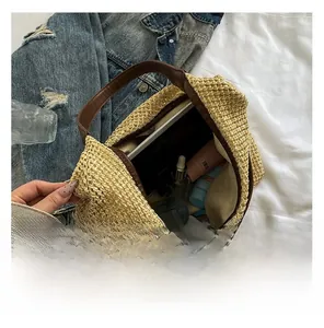 Detailed top view of large straw tote bag with brown leather handles on white fabric