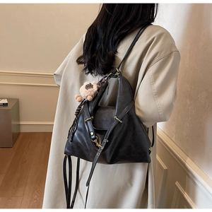 Detail view of large black tote bag with sheep pendant and golden metallic hardware