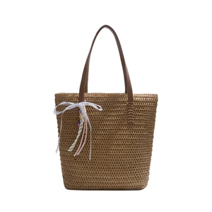Summer straw tote bag with brown leather handles and a white lace bow charm