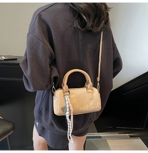 Detail view of a beige Boston bag featuring decorative woven cord on a street-style model