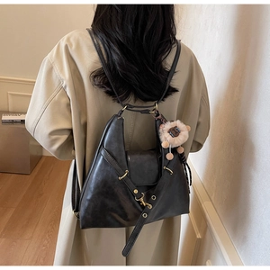 Close-up of a black textured leather hobo bag with gold zippers and a sheep charm