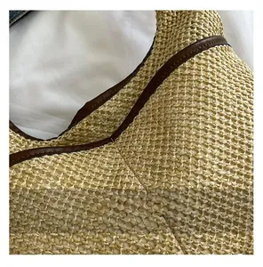 Detail view of woven straw tote bag featuring brown leather trim and natural fiber texture