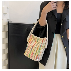 Detail view of the colorful woven striped tote bag with cream white leather shoulder strap
