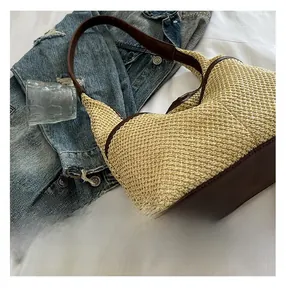 Detailed view of beige straw woven tote with dark brown leather trim and stitching details