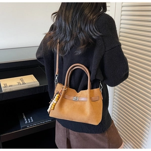 Vue détaillée du sac seau en daim marron avec pendentif en perles colorées et boucle en métal