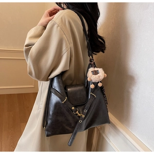 Close-up of black oil-wax leather tote bag with gold metal hardware and alpaca charm