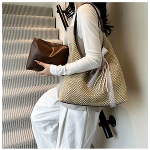 Detail of woven straw bucket bag with lace bow and internal brown leather zip pouch