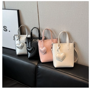Detail view of four glossy patent leather mini tote bags with heart charms in assorted colors
