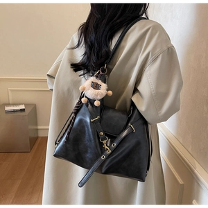 Detail view of black vintage faux leather tote bag with metal eyelets and plush charm