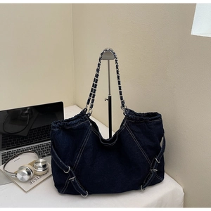 Detail of blue denim tote bag with drawstring closure and metal buckle on office desk