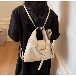 Detail of minimalist beige faux leather tote bag with gold hardware and plush charm