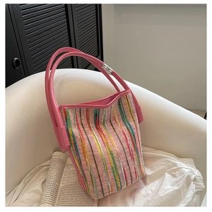 Detalle de bolso tipo cubo de punto rosa con rayas de colores y asas dobles de cuero