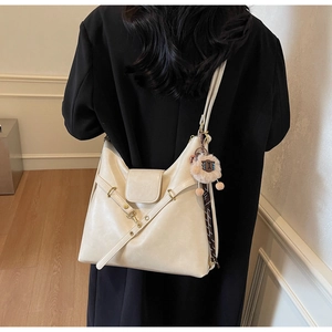 Rear view of model wearing a creamy beige leather tote bag with a cute lamb pendant