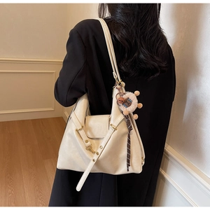 Close-up of cream leather tote bag with lychee texture and cute lamb charm accessory