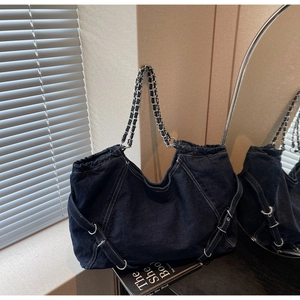 Detail of dark blue denim tote featuring white contrast stitching and woven chain strap