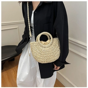 Detail of straw half-moon bag with drawstring closure worn by a model in casual style