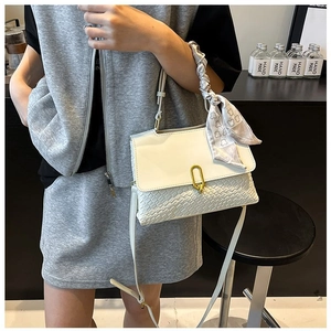 Detailed view of woven texture and scarf-wrapped handle on a white crossbody bag