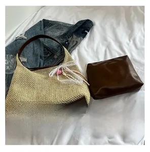 Detail of hand-woven straw bucket bag with brown leather base and lace bow charm
