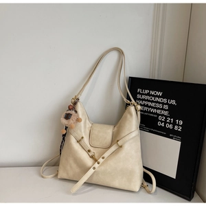 Detail of cream hobo tote bag featuring pebbled leather texture and cute lamb charm accessory